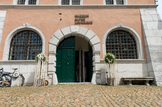 geöffnete Eingangstüren des Museums, links und rechts der Türe Blumenschmuck